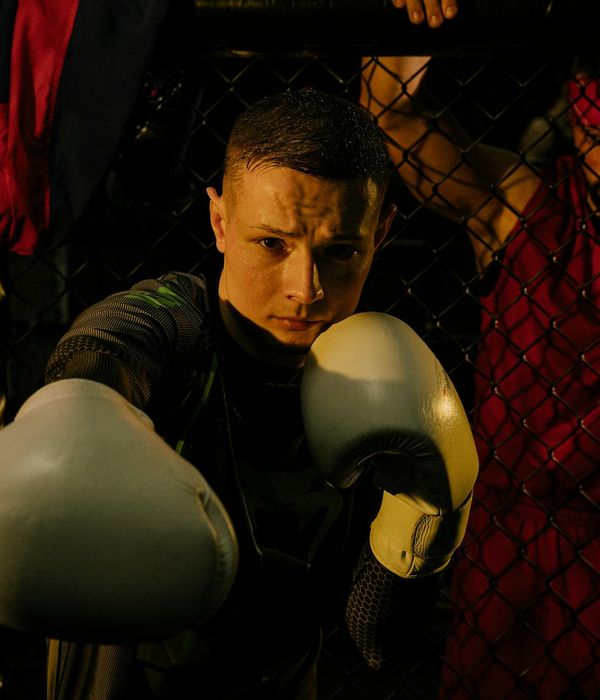 Man performing a controlled strength exercise in a dark room with magenta light.